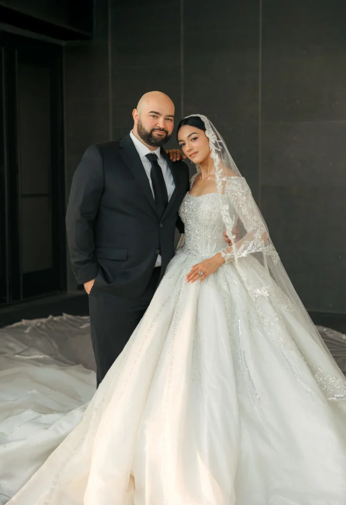 Bride and groom posing together, with the bride holding a white bouquet