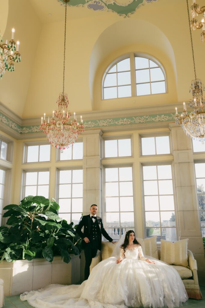 Wedding couple in a grand interior with tall windows and chandeliers