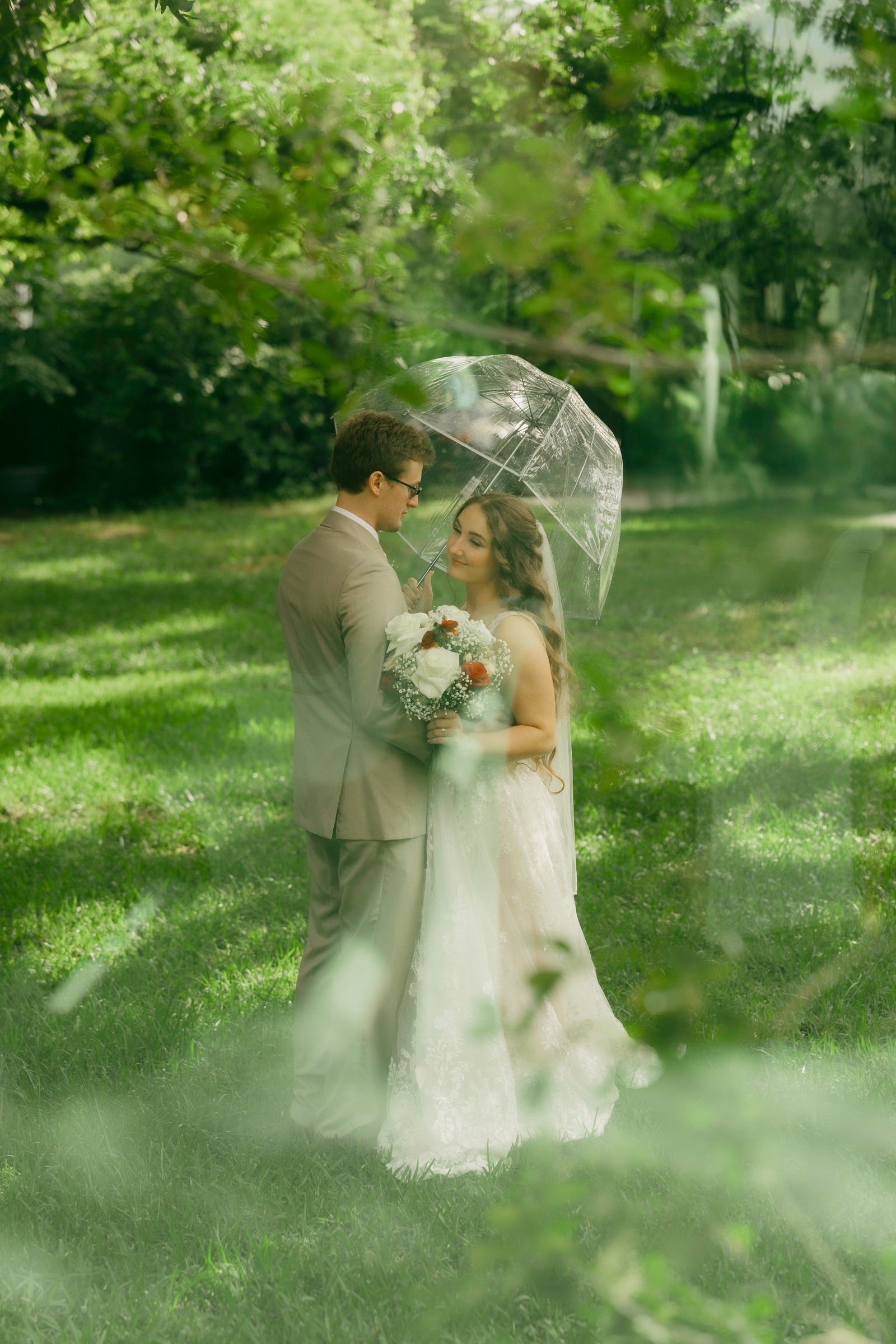 Gabe and Krista kissing beneath a clear umbrella at Brighton Abbey