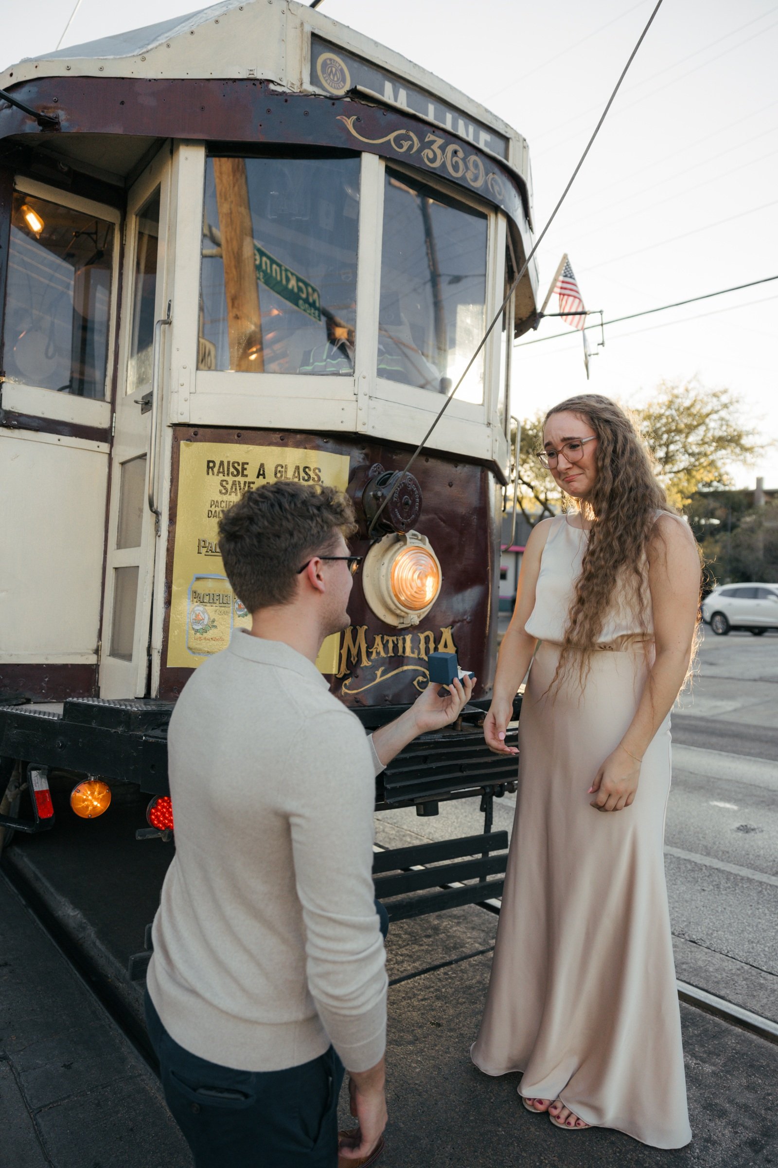 Gabe proposing to Krista beside a vintage trolley